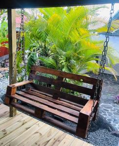 a wooden swing sitting on a patio with palm trees at Chambre indépendante in Basse-Terre +2 photos