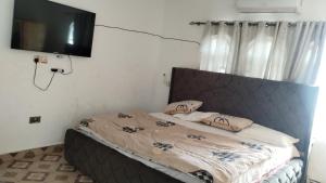 a bedroom with a bed with a television on the wall at Modern Way Guesthouse in Kasoa