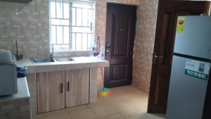 a kitchen with a sink and a refrigerator and a window at Modern Way Guesthouse in Kasoa