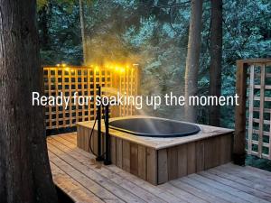 a jacuzzi tub on a deck in the woods at Creekside Bunkies in Roberts Creek