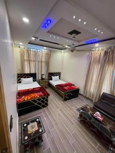 a room with two beds and a couch in it at Royal swiss Hotel Khanpur in Khānpur