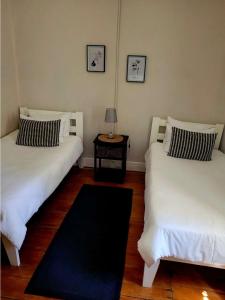 two beds in a room with a lamp on a table at Boer & Brit, Graaff-Reinet in Graaff-Reinet +2 photos