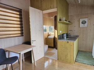 a kitchen with a sink and a table and a bathroom at Piestātne Riverside Cabins with Sauna, Hot Tub & Private Pier in Katlakalns