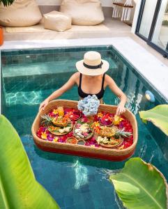 a person with a tray of food in a swimming pool at Casa pumara loft in Kerobokan