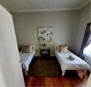 a bedroom with two beds and a painting on the wall at Boer & Brit, Graaff-Reinet in Graaff-Reinet