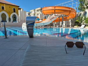 a swimming pool with a slide and a pair of sunglasses at Luxury apartment with panoramic sea view ruby in Alanya