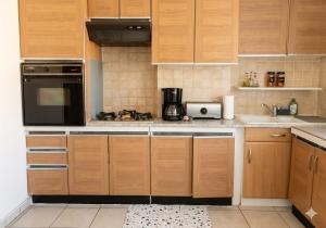 a kitchen with wooden cabinets and a black microwave at Au Bon Pasteur RDC proche des voies routières et du centre ville in Cholet