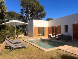 a house with a swimming pool and an umbrella at Vivez Cala Morell! in Cala Morell