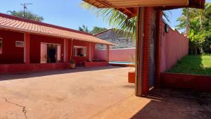 a red building with a palm tree in front of it at Recanto da Saudade, 3 Quartos, Piscina, Churrasqueira in Boituva