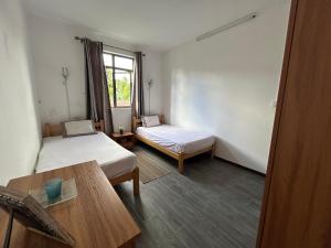 a room with two beds and a table and a window at The cozy nest in Curepipe