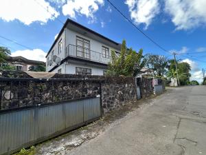 a white house with a fence in front of a street at The cozy nest in Curepipe