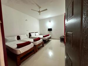 a room with three beds and a tv in it at Bougainvillea in Chikmagalūr