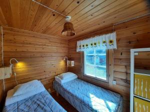 a log cabin with two beds and a window at Mökki Katjukka, Ruka in Kuusamo