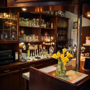 a bar with a vase of yellow flowers on a table at Mecklenburger Hof in Parchim