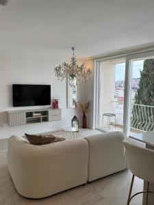 a white living room with a couch and a tv at Sea view in Dubrovnik