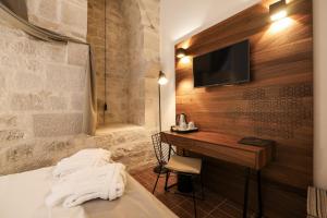 a hotel room with a bed with a desk and a television at Heritage Hotel Maskovica Han in Pakoštane