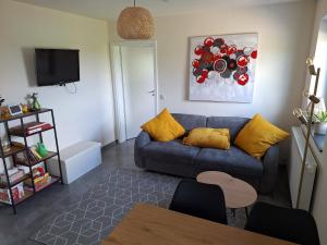 ein Wohnzimmer mit einer blauen Couch und gelben Kissen in der Unterkunft Studio Keppelborn in Sankt Vith