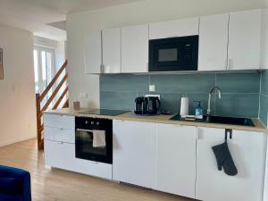 a kitchen with white cabinets and a microwave at Duplex d Iroise rénové 2 chambres Centre Gouesnou Parking & Wifi in Gouesnou +26 photos