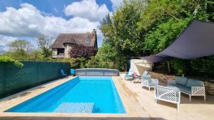a swimming pool in a yard with chairs and a house at Les Maisons de Mélody in Houlbec-Cocherel