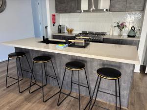 a kitchen with three bar stools at a counter at Urban Pause - Donnybrook in Donnybrook +17 photos
