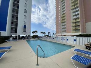 a swimming pool with blue lounge chairs and buildings at Oceanfront Condo, Steps to the Beach in Myrtle Beach