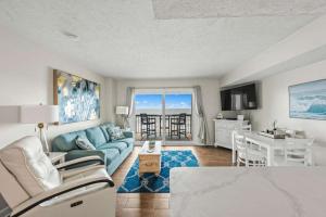 a living room with a blue couch and a table at Oceanfront Condo, Steps to the Beach in Myrtle Beach