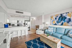 a living room with a blue couch and a kitchen at Oceanfront Condo, Steps to the Beach in Myrtle Beach