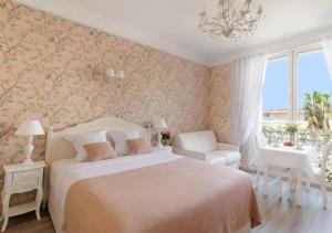 a bedroom with a bed and a chair and a window at Cannes Imperial Croisette Palais Miramar in Cannes