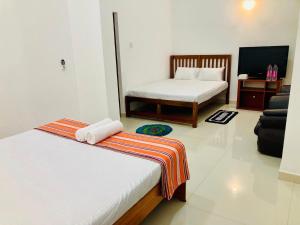 a room with two beds and a tv and a couch at Sky Mansion Athurugiriya in Athurugiriya