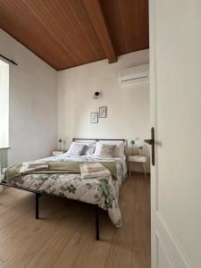 a white bedroom with a bed and a wooden ceiling at Vintage House in Asciano