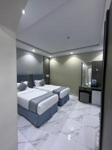 a hotel room with two beds and a mirror at فندق اجنحه البيداء فرع2 AlBaydaa Suites Hotel Branch in Medina +29 photos