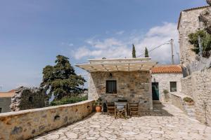 a stone house with a table and chairs on a patio at Anemolithos Mani's House in Areopoli