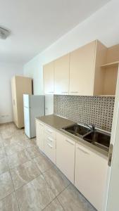 an empty kitchen with white cabinets and a sink at Dhermi Light Rooms in Dhërmi