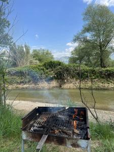 a grill sitting in the grass next to a river at Damiano House in Sarandë