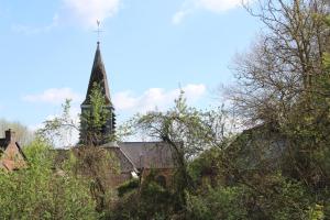 an old church with a steeple with trees in the foreground at Country house in Erloy, Oise valley in Erloy