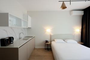 a white bedroom with a bed and a sink at Mira Seaview Studio Apartment in Batumi in Batumi