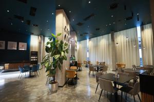a restaurant with tables and chairs and a plant at Mira Seaview Studio Apartment in Batumi in Batumi