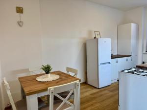 a kitchen with a wooden table and a white refrigerator at StayU Apartment in Ústí nad Labem