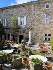 a courtyard with tables and chairs and a building at Le Manoir du Raveyron in Vallon-Pont-dʼArc
