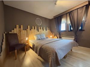 a bedroom with a large bed and a chair at Noax gite Durbuy in Durbuy