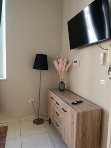 a room with a wooden dresser with a television on the wall at Casa vacanze So Suite 24 in Reggio di Calabria