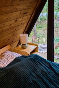 a bedroom with a bed and a lamp on a table at Leśna Chatka in Wola Polska