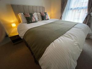 a bedroom with a large white bed with a window at 3 Stable Mews in Holsworthy