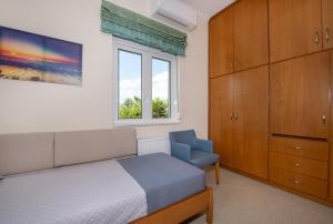 a bedroom with a bed and a chair and a window at Socrates Holidays Apt 3 with Pool near the Beach in Kamisianá +56 photos