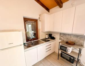 a kitchen with white cabinets and a sink and a microwave at Casa Ana Istria 1 in Savudrija +6 photos