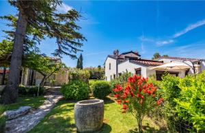 a garden with red flowers and a white house at Casa Ana Istria 1 in Savudrija