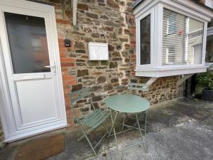 a table and a chair next to a brick wall at 3 Stable Mews in Holsworthy