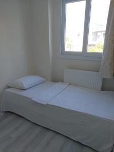 a bed in a white room with a window at Alaçatı evi in Alaçatı