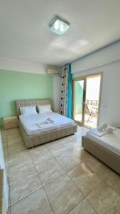 a bedroom with two beds and a balcony at Dhermi Light Rooms in Dhërmi