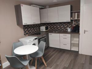 a small kitchen with white cabinets and a table and chairs at Maison-Home-ZuHause in La Calamine